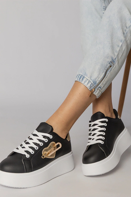 Schwarze Sportschuhe mit herzförmigem... Schwarze Sportschuhe mit herzförmigem...