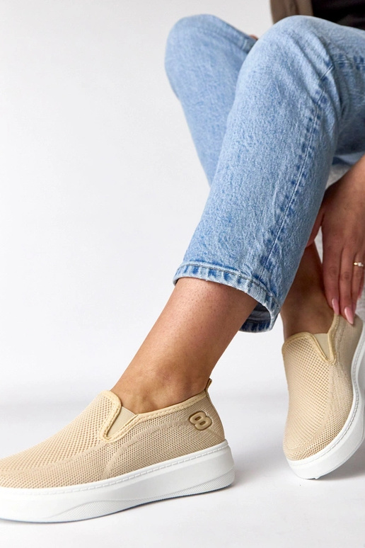 Zandkleurige stoffen sneakers op een...