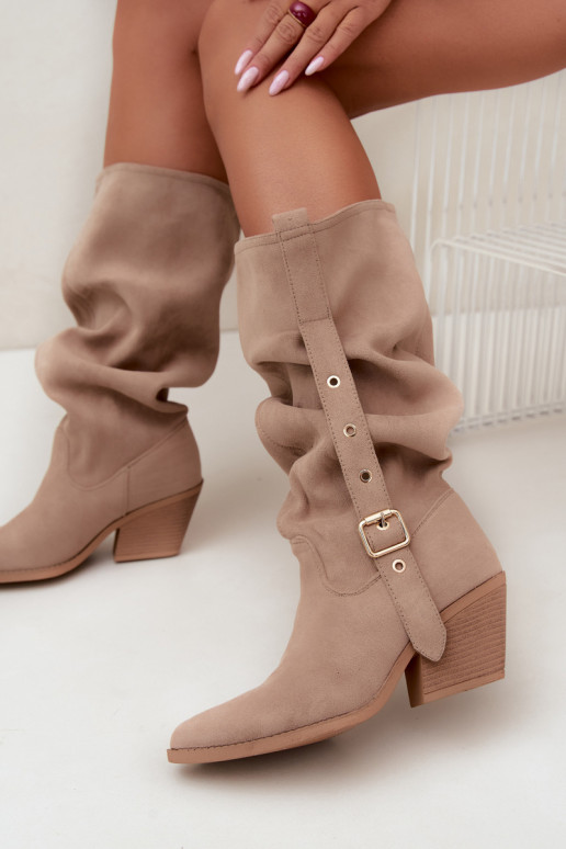 gekruiste dames lange laarzen in cowboystijl met riemen en hakken in zand Adria